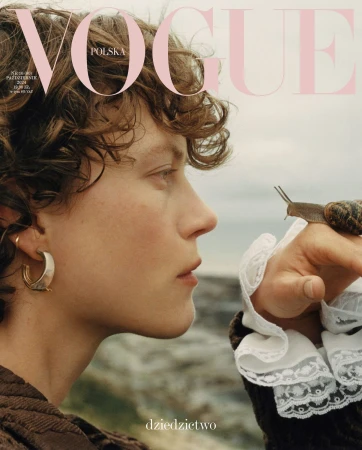 Close-up profile portrait of a model with curly brown hair looking at a small snail on their hand by Kulesza & Pik.