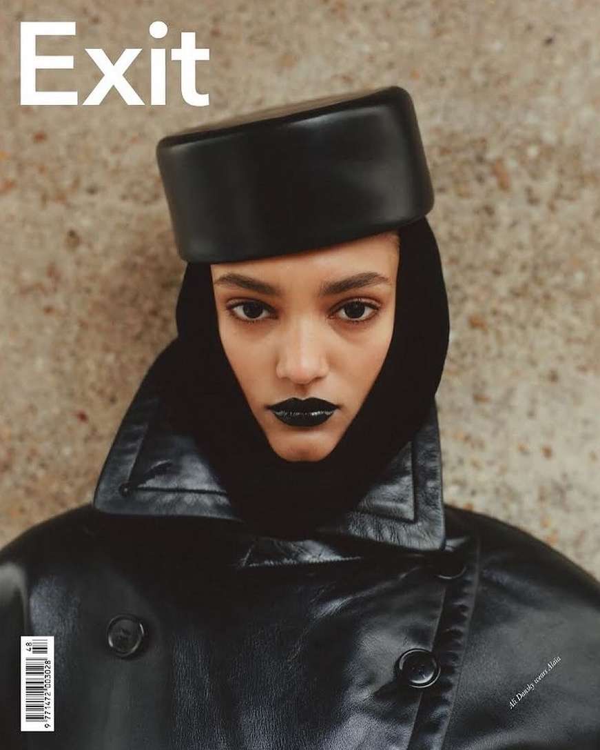 Magazine cover featuring a model with dark lipstick and a leather hat and jacket against a textured background.
