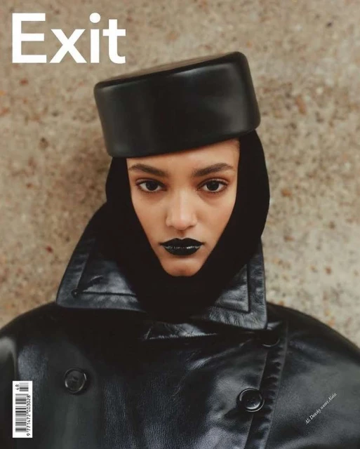 Magazine cover featuring a model with dark lipstick and a leather hat and jacket against a textured background.
