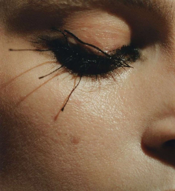 Extreme close-up of a woman's eye, dramatic long black lashes heavily coated with mascara, and smooth skin in a beauty shot.