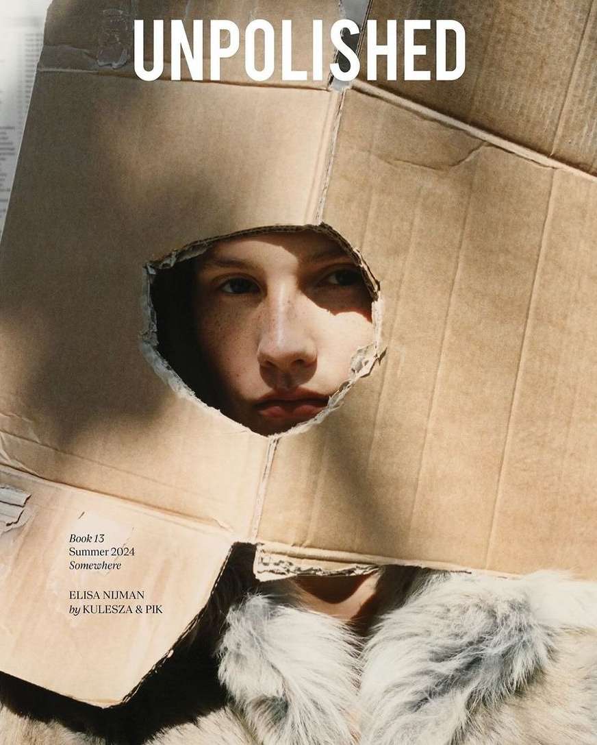 Model wearing a cardboard box over head with a jagged cutout framing face, photographed by Kulesza & Pik.