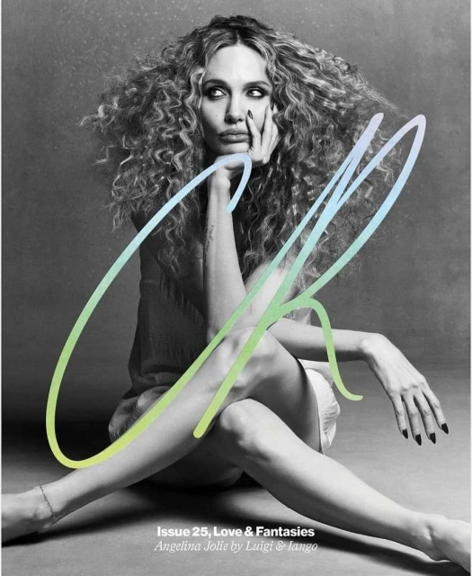 Monochrome magazine cover shot of Angelina Jolie with curly hair, sitting cross-legged, leaning on her hand, with large stylized text.