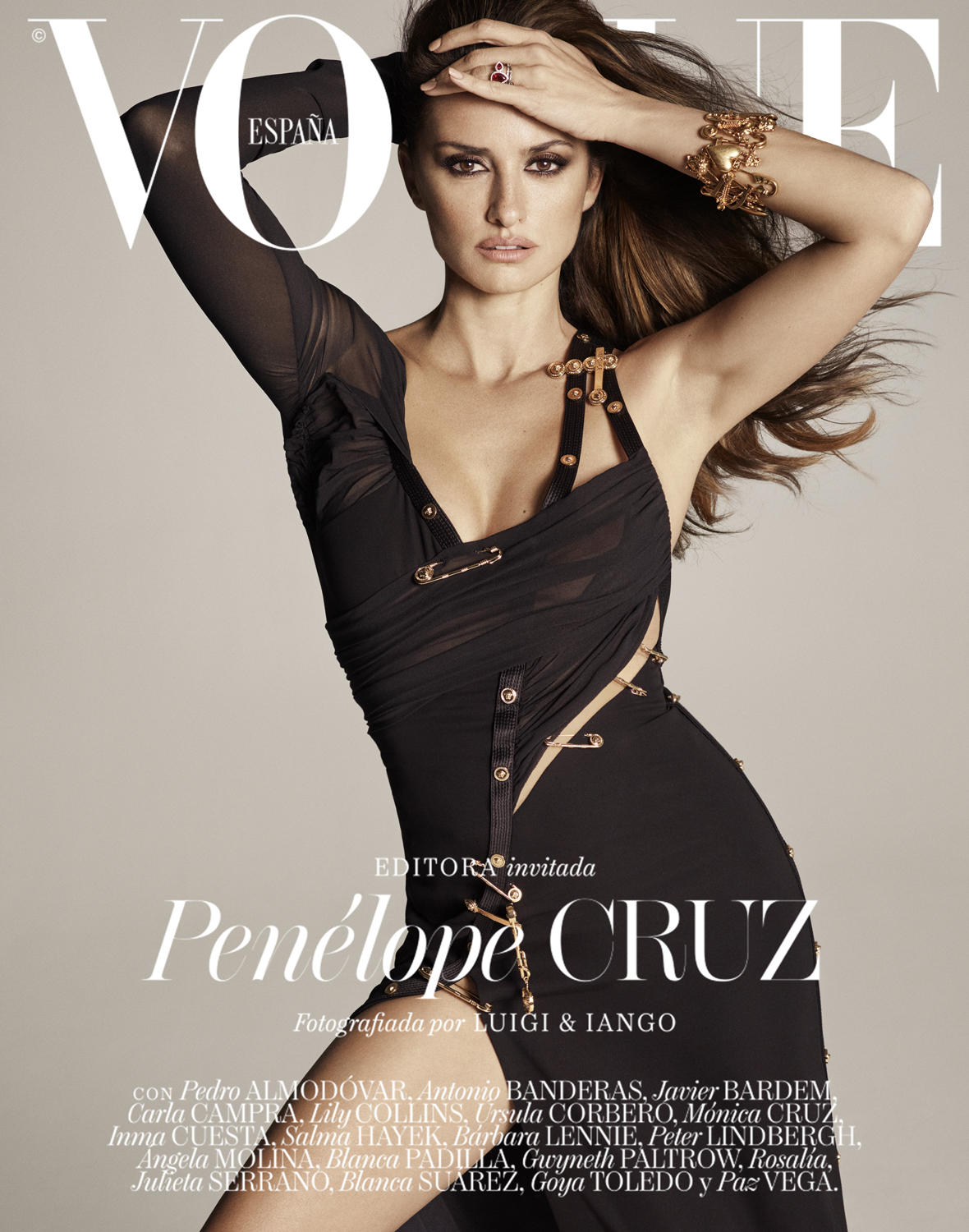 Vogue España cover featuring Penélope Cruz wearing a black dress with gold safety pin details and gold jewellery against a grey background.