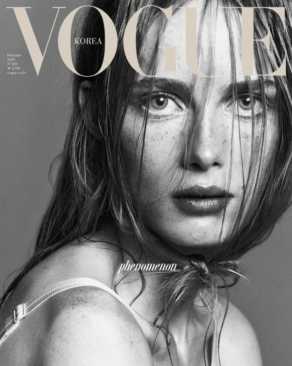 Monochromatic close-up of a fair-skinned adult woman with freckles and light brown hair on the cover of Vogue Korea magazine.