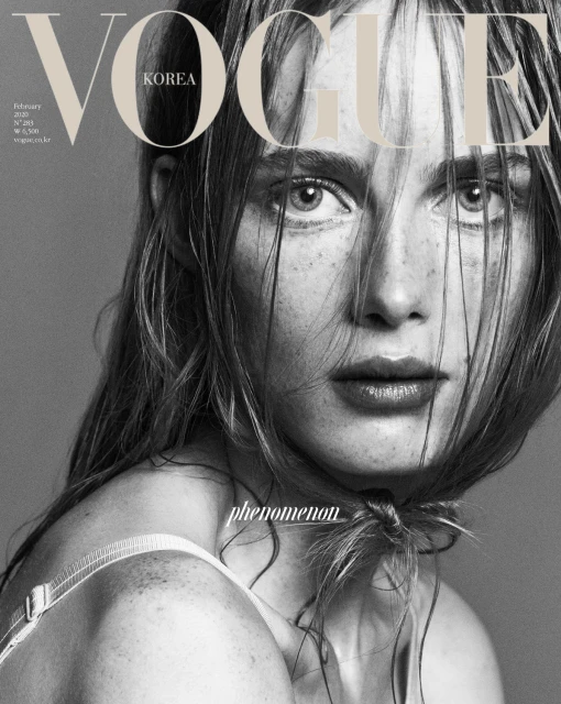 Monochromatic close-up of a fair-skinned adult woman with freckles and light brown hair on the cover of Vogue Korea magazine.
