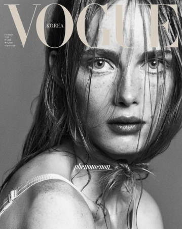 Monochromatic close-up of a fair-skinned adult woman with freckles and light brown hair on the cover of Vogue Korea magazine.