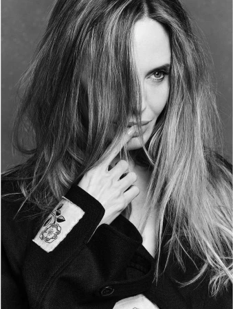 Close-up monochrome portrait of a woman with long hair partially covering her face, wearing a dark jacket.