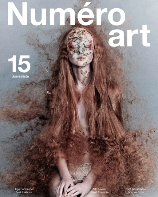 Surreal fashion cover featuring a woman with long wavy red hair and face art on a light blue backdrop, promoting Numéro Art.