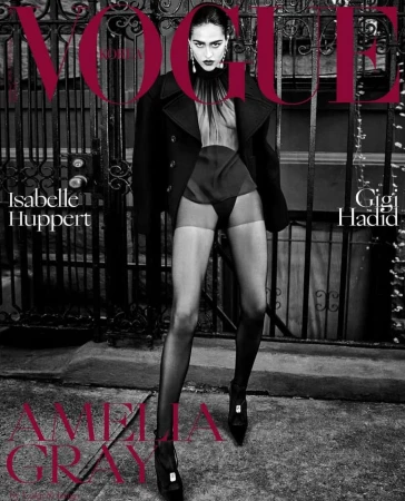 Fashion magazine cover featuring a model in a black coat and sheer lingerie, set against a wrought iron fence and city street backdrop.