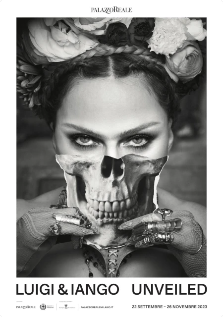 Black and white portrait of a woman wearing a floral headpiece, with a skull overlay, jewellery, and dark eye makeup in a studio.