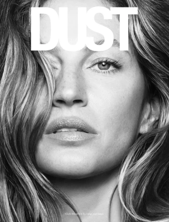 Close-up monochrome portrait of a woman with long layered hair, freckles, and bold white magazine typography across the top.