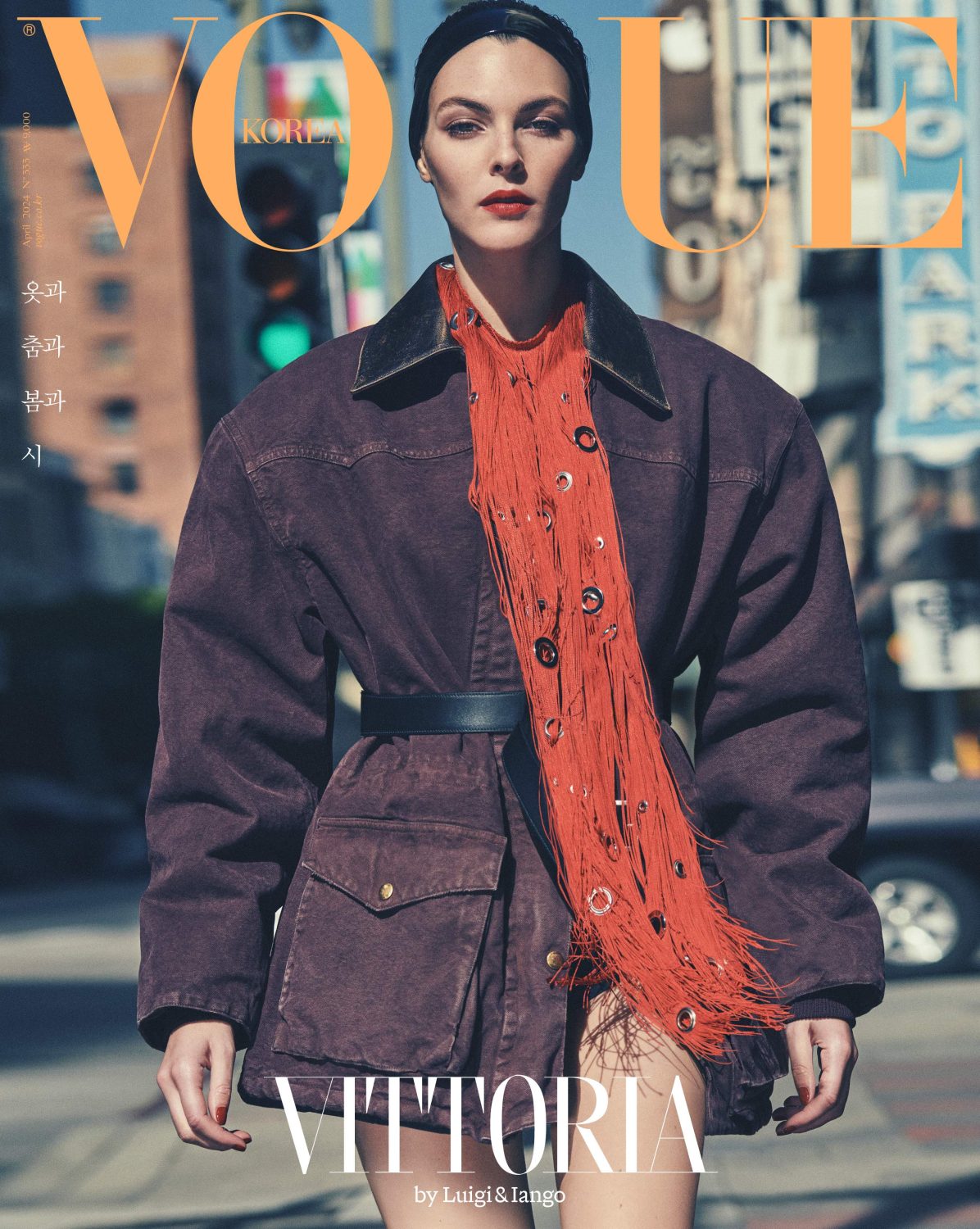 Vittoria Ceretti graces Vogue Korea cover in oversized jacket, red fringed top, and black headband, set against an urban backdrop.