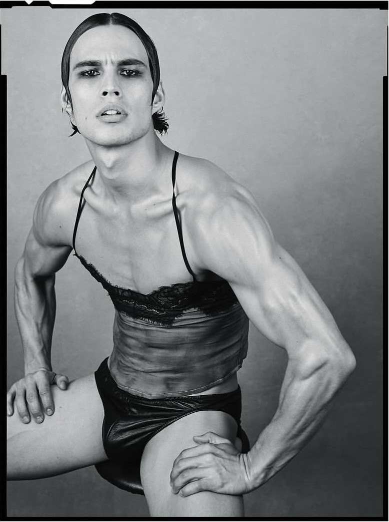 Black and white portrait of a muscular man wearing a lace top and briefs, photographed by Luigi and Iango.
