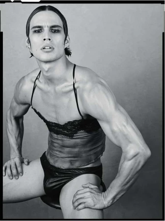 Black and white portrait of a muscular man wearing a lace top and briefs, photographed by Luigi and Iango.