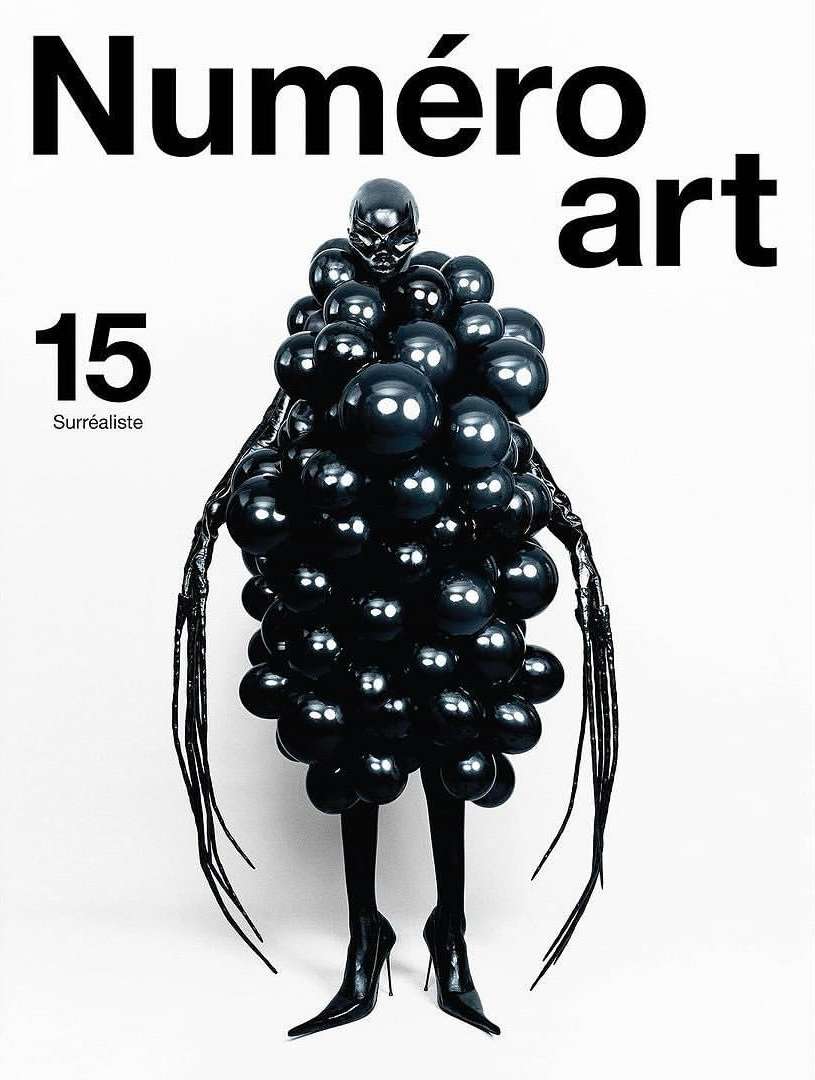 Black-clad figure covered in glossy black balloons stands in front of a stark white backdrop for Numero art magazine cover.