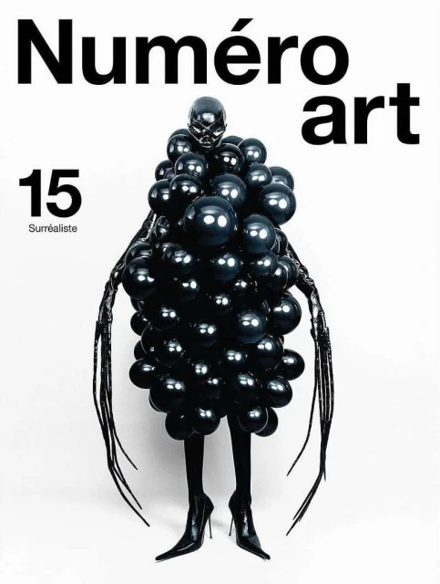 Black-clad figure covered in glossy black balloons stands in front of a stark white backdrop for Numero art magazine cover.