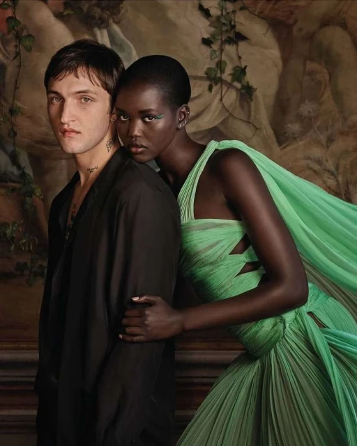 A fashion editorial featuring a caucasian man and a black woman wearing a pastel green gown, posing in front of a Renaissance-style backdrop.