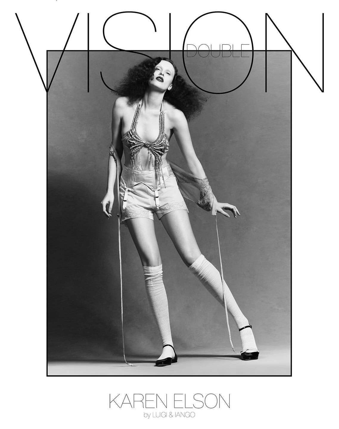 Black and white fashion portrait of Karen Elson wearing shorts, top, knee socks and heels against a grey studio background with text overlay.
