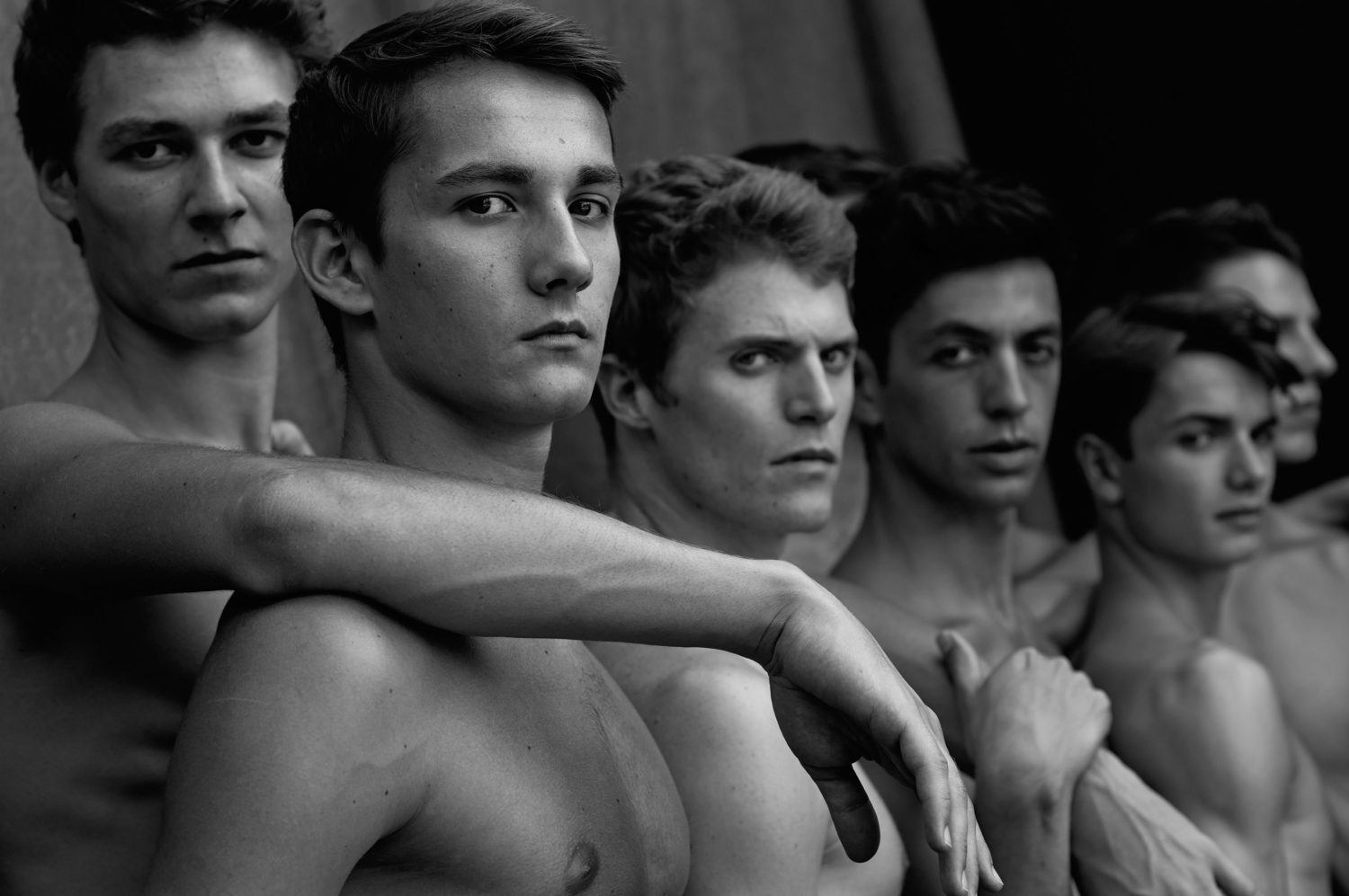 Black and white portrait of a group of young adult men standing close together, looking directly at the camera with serious expressions.
