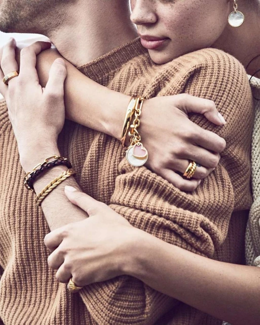 Close-up of a couple embracing, showcasing bracelets and rings. The focus is on the jewelry and the intimate connection between the two people.