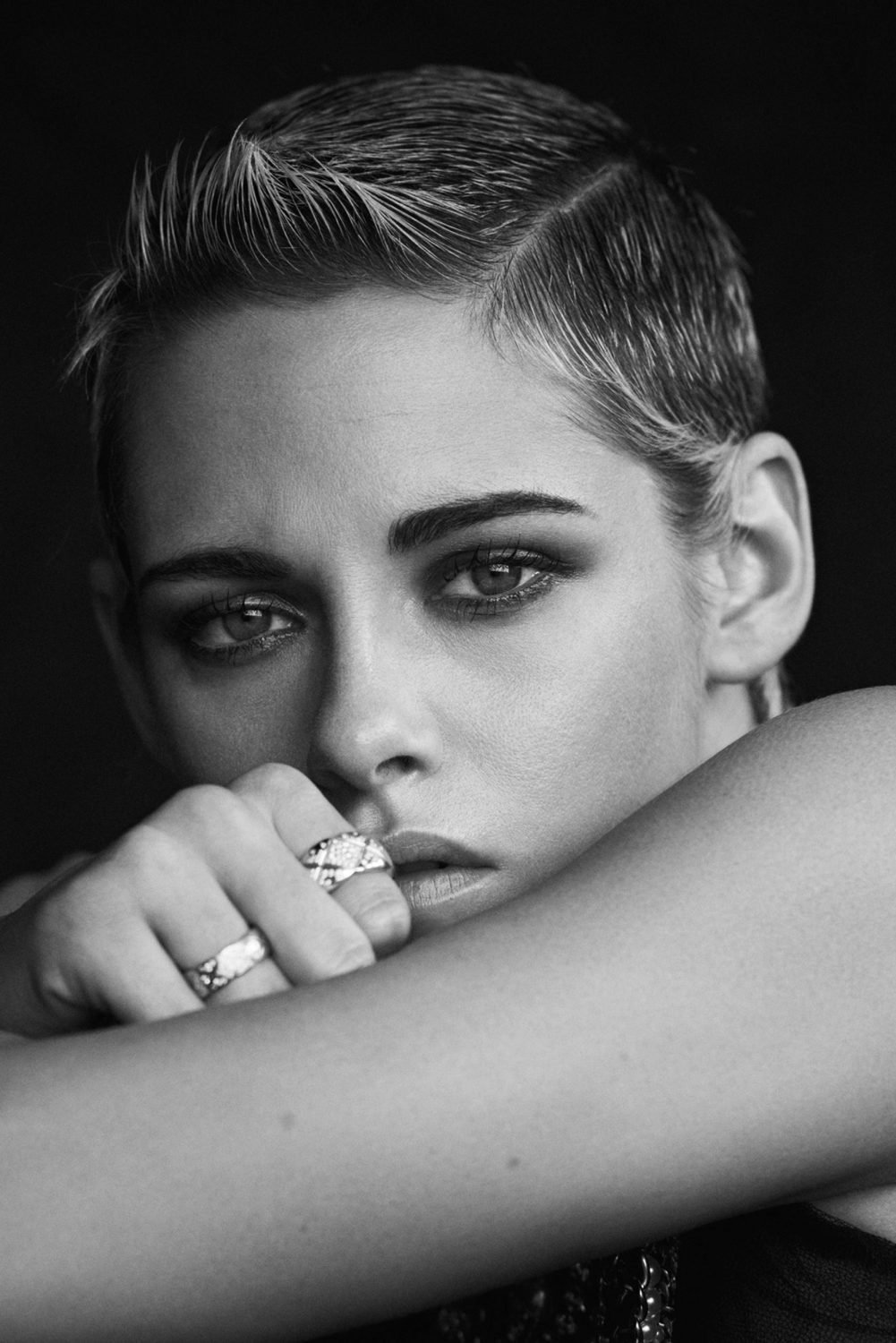 Close-up portrait of Kristen Stewart with short cropped hair and rings on her fingers, directed by Matthew Brookes.