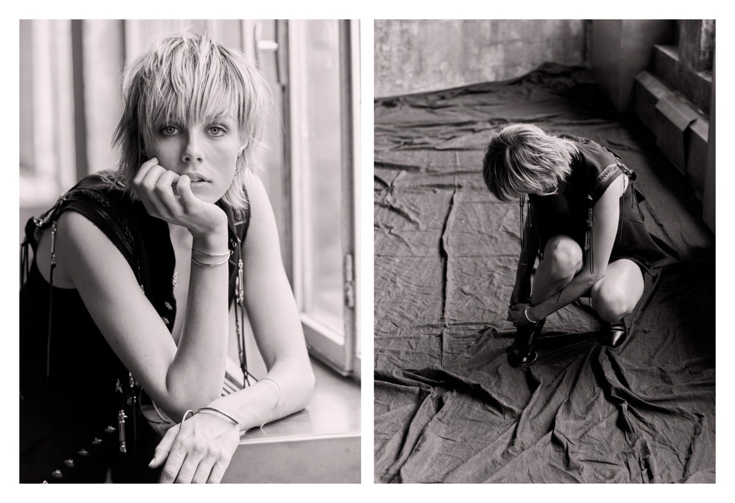 Monochrome portrait of a fair-skinned woman with short blonde hair in a sleeveless top, resting her chin on her hand by a window.