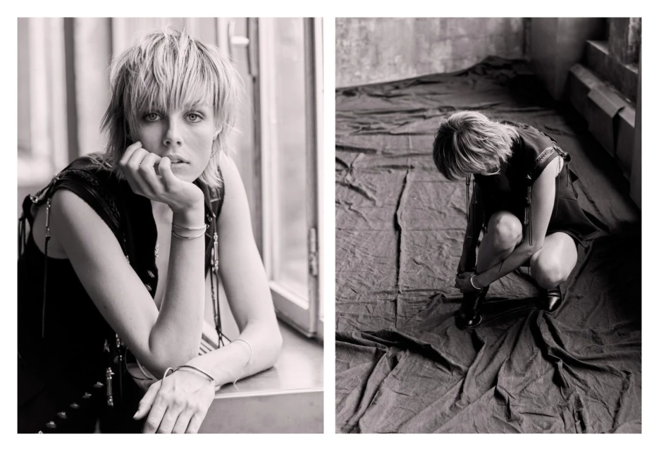 Monochrome portrait of a fair-skinned woman with short blonde hair in a sleeveless top, resting her chin on her hand by a window.
