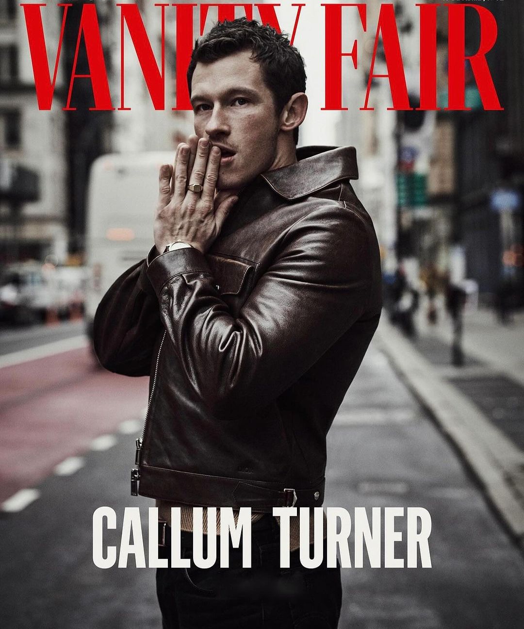 Callum Turner wearing a dark brown leather jacket on a city street, photographed by Matthew Brookes for Vanity Fair magazine cover.