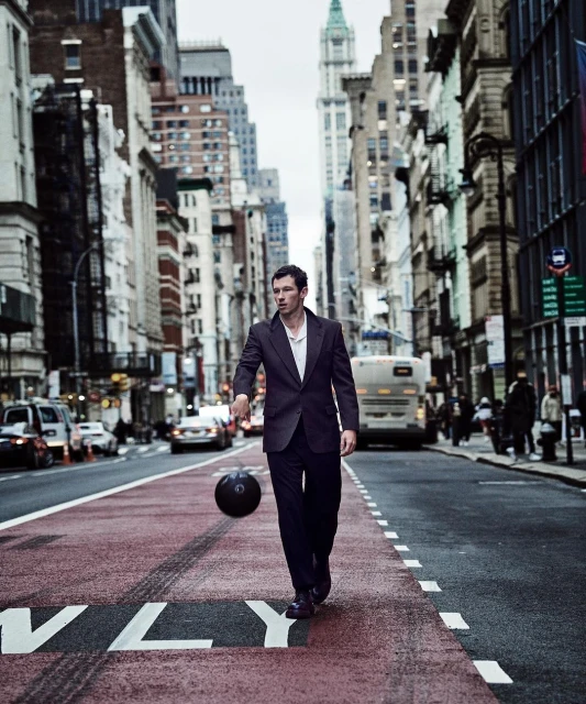 Young man in suit dribbles basketball in city street, surrounded by tall buildings and urban scene. Stylish and athletic concept.