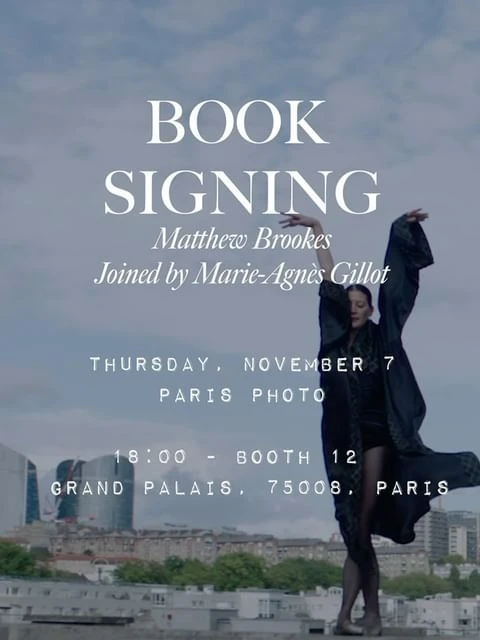 Elegant event poster featuring a woman in flowing robe striking a pose against a Paris cityscape, advertising a book signing.