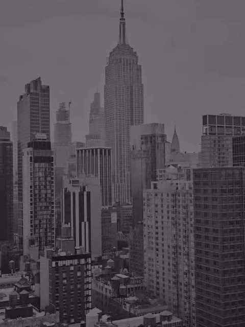 Monochrome cityscape featuring the Empire State Building amidst surrounding skyscrapers under an overcast sky in an urban environment.