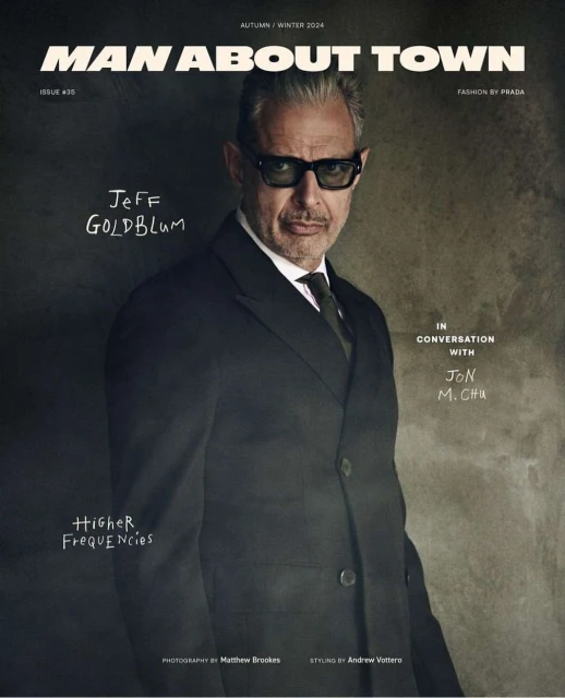Man About Town magazine cover featuring Jeff Goldblum in a suit and tie, shot in a photo studio with soft lighting and a neutral background.