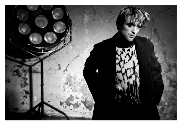 Robert Pattinson wearing a patterned sweater and dark coat in a black and white portrait directed by Matthew Brookes.