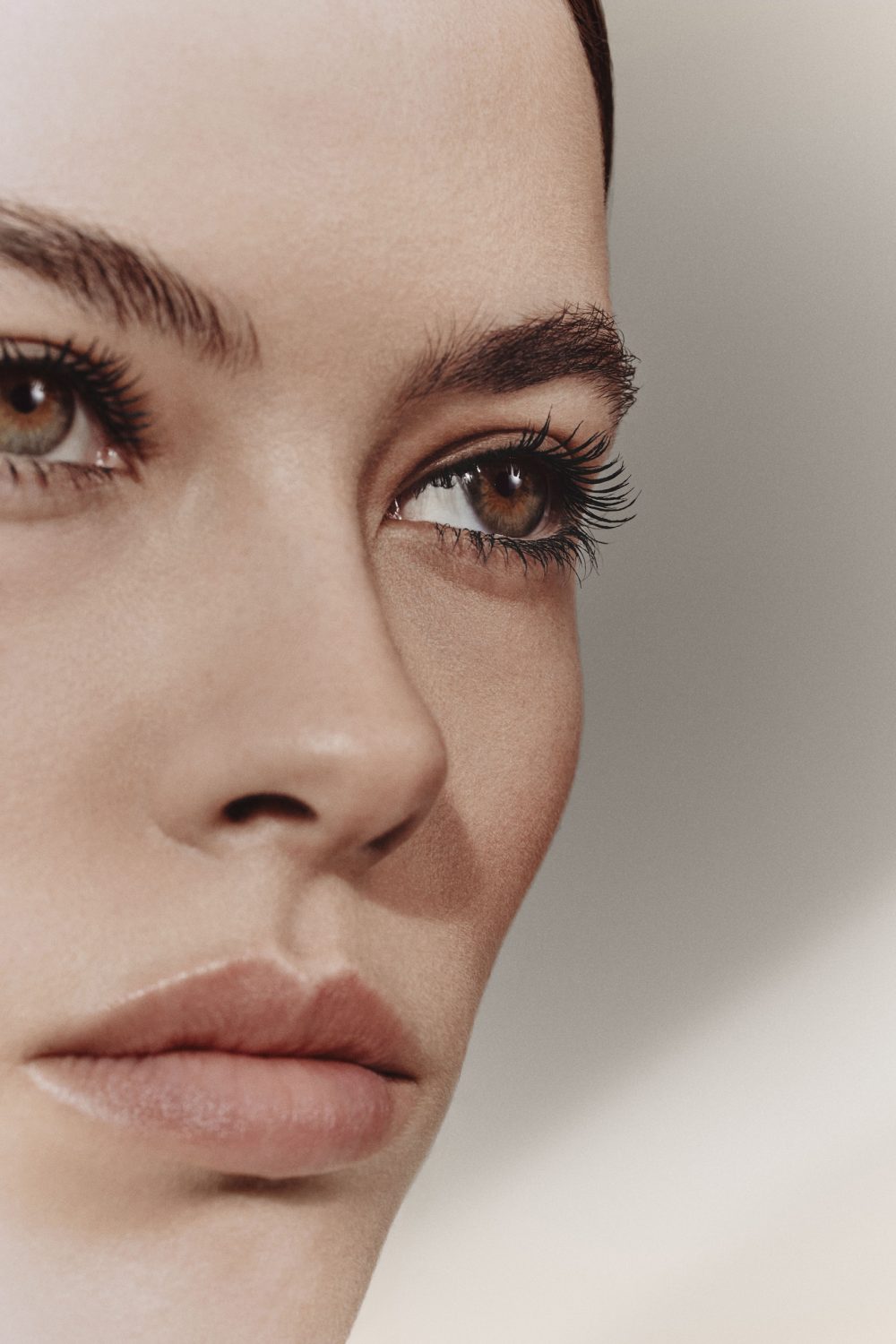 Close-up portrait of a woman's face highlighting eyes and eyebrows against a neutral background.