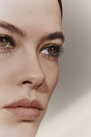 Close-up portrait of a woman's face highlighting eyes and eyebrows against a neutral background.