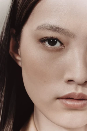 Close-up portrait of an East Asian woman's face highlighting natural makeup and skin texture.