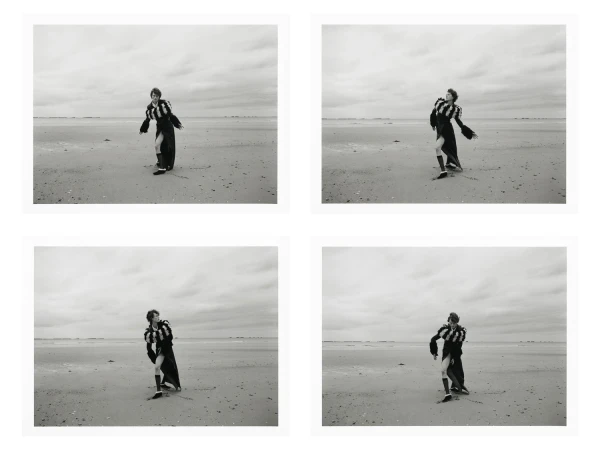 A four-panel black and white photographic print showing a model posing on a wide sandy beach under an overcast sky.
