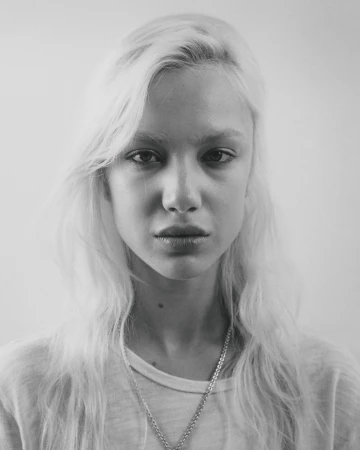 Portrait of a young blonde woman with long hair and a light t-shirt against a plain background