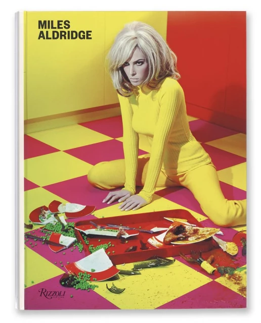 Book cover photo of a blonde woman in a yellow suit kneeling near a red serving tray with broken dishes, food, and liquid spillage.
