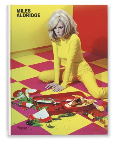 Book cover photo of a blonde woman in a yellow suit kneeling near a red serving tray with broken dishes, food, and liquid spillage.