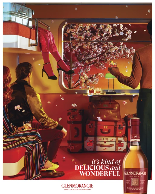 Glenmorangie scotch whiskey ad with people on a train, vintage suitcases, and cherry blossom decor, promoting a delicious and wonderful taste.