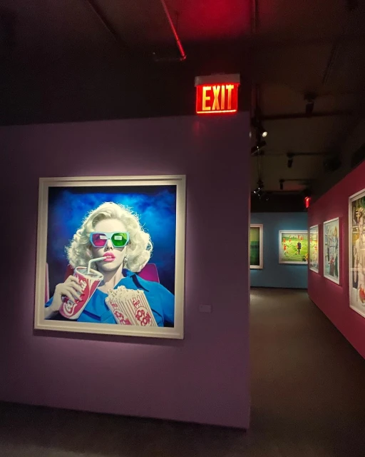 Artwork on a purple gallery wall shows a woman in 3D glasses holding a drink and popcorn with gallery visitors in the background.
