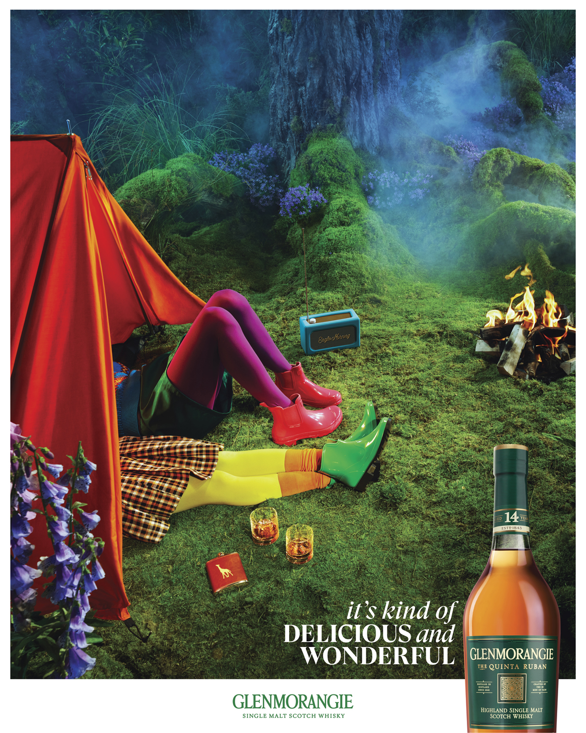 Eye-level outdoor shot of a colorful camping scene with a tent, two people wearing boots, a radio, a campfire, and a bottle of Glenmorangie.