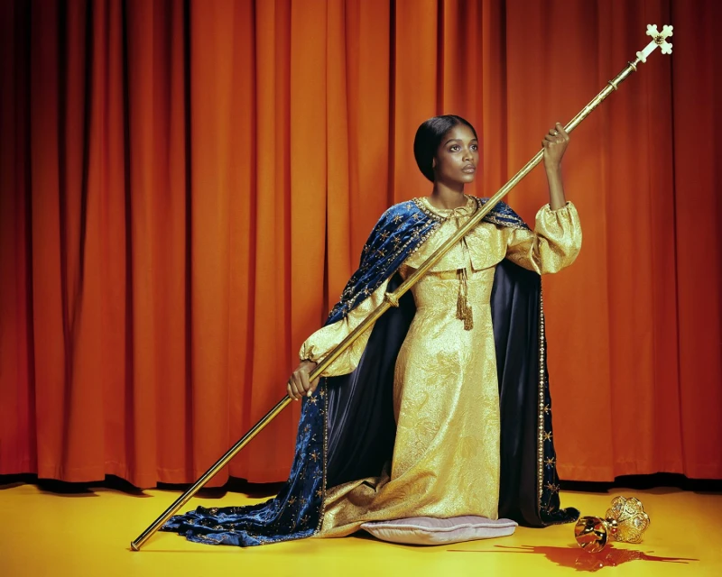 Elegant woman in a gold dress and blue cape holds a golden scepter, standing against a red curtain, on a yellow floor with a fallen crown.