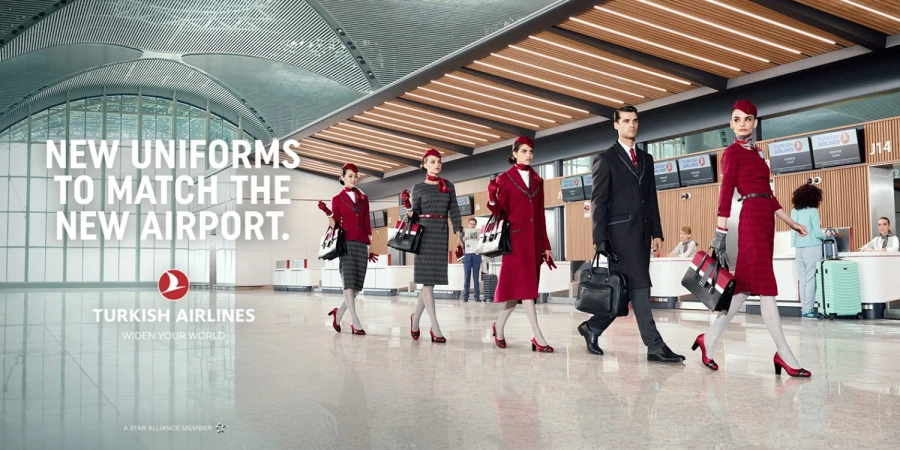 Turkish Airlines ad featuring airline staff in new uniforms walking through an airport terminal with modern architecture and lighting.