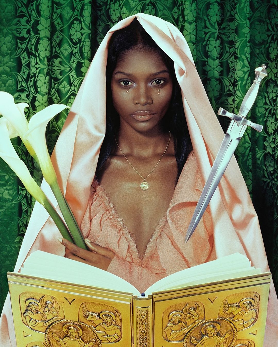 Elegant portrait of a Black woman in a draped gown and head covering, holding white flowers and a sword, with an open, ornate book.