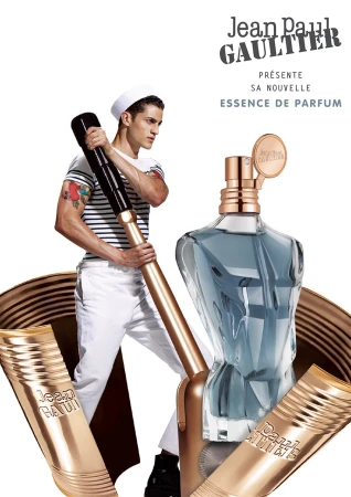 Jean Paul Gaultier fragrance advertisement features male model in sailor hat, perfume bottle, and product tubes on a white backdrop.