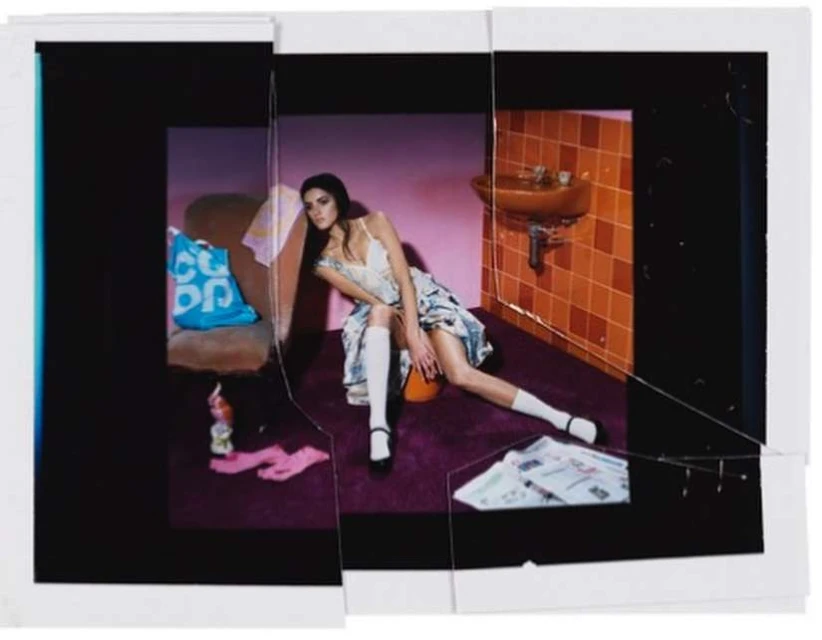 Indoor fashion shot of a female model wearing a patterned dress and white socks while leaning against a wall in a bathroom setting.