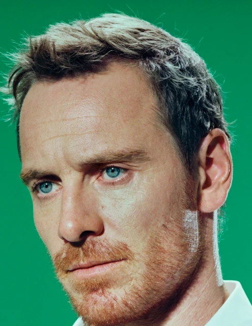Close-up portrait of an adult male with light hair and a reddish beard against a green background, focusing on his facial features.
