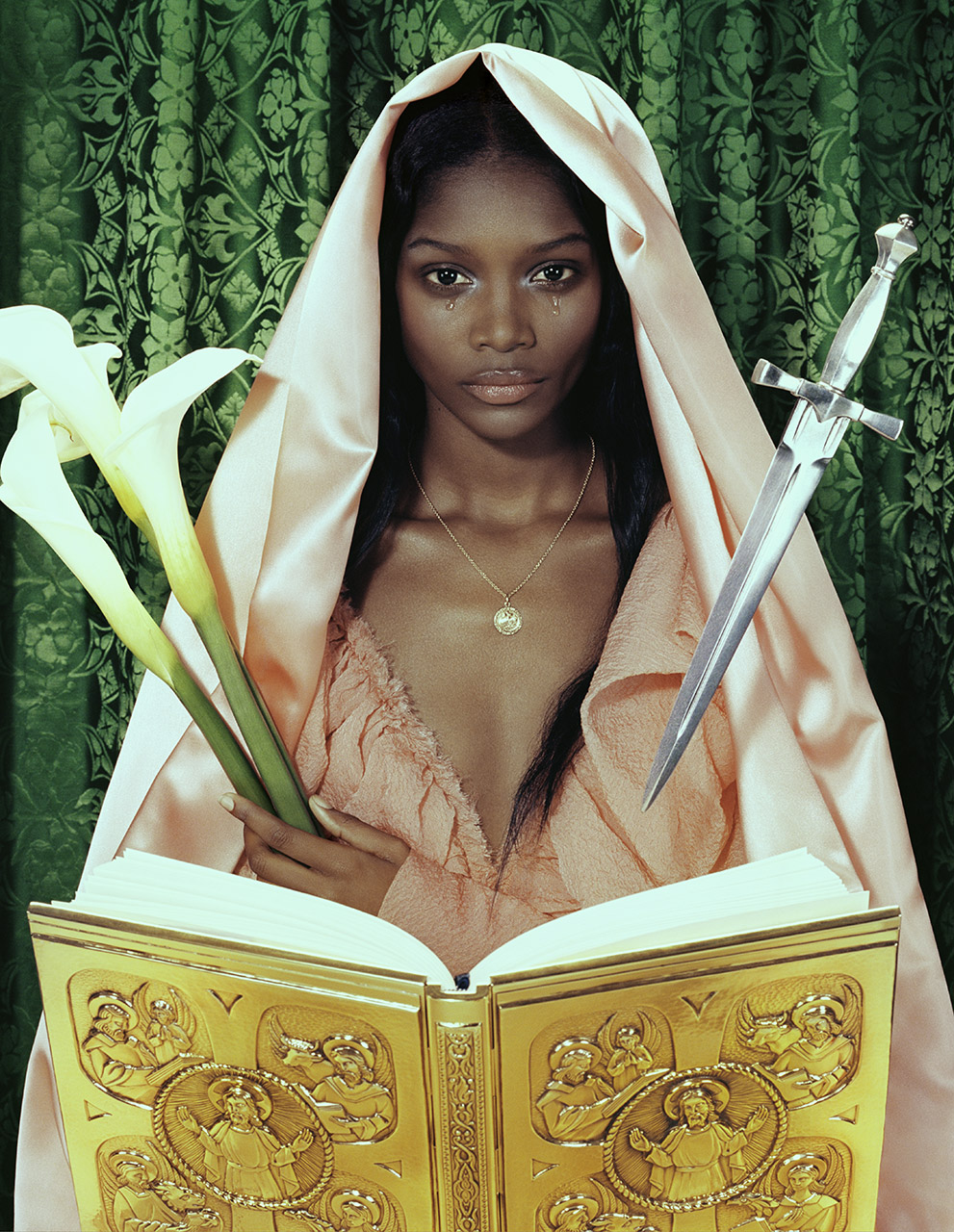 A woman with dark skin and tears is wearing a draped robe and holding lilies and a dagger in front of a gold book.